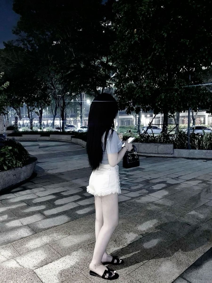 Gái xinh mặc áo phông xám và quần shorts trắng ra phố đêm