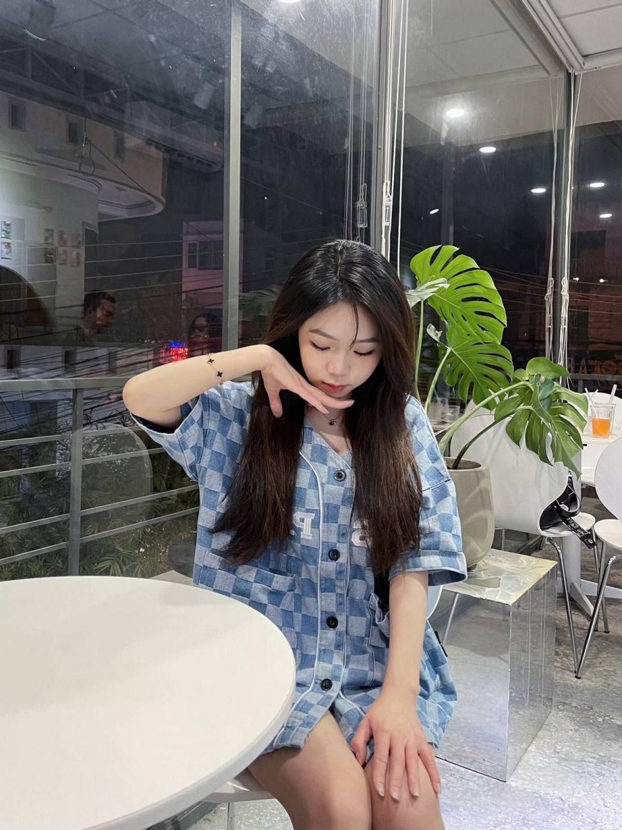 Gái xinh mặc áo sơ mi hoa tiết, ngồi trong quán cà phê hiện đại