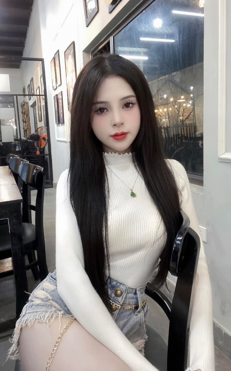Gái xinh mặc áo thun trắng và quần shorts jean tại quán cà phê
