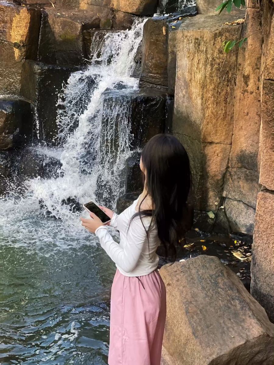 Gái xinh mặc áo trắng và chân váy hồng bên thác nước