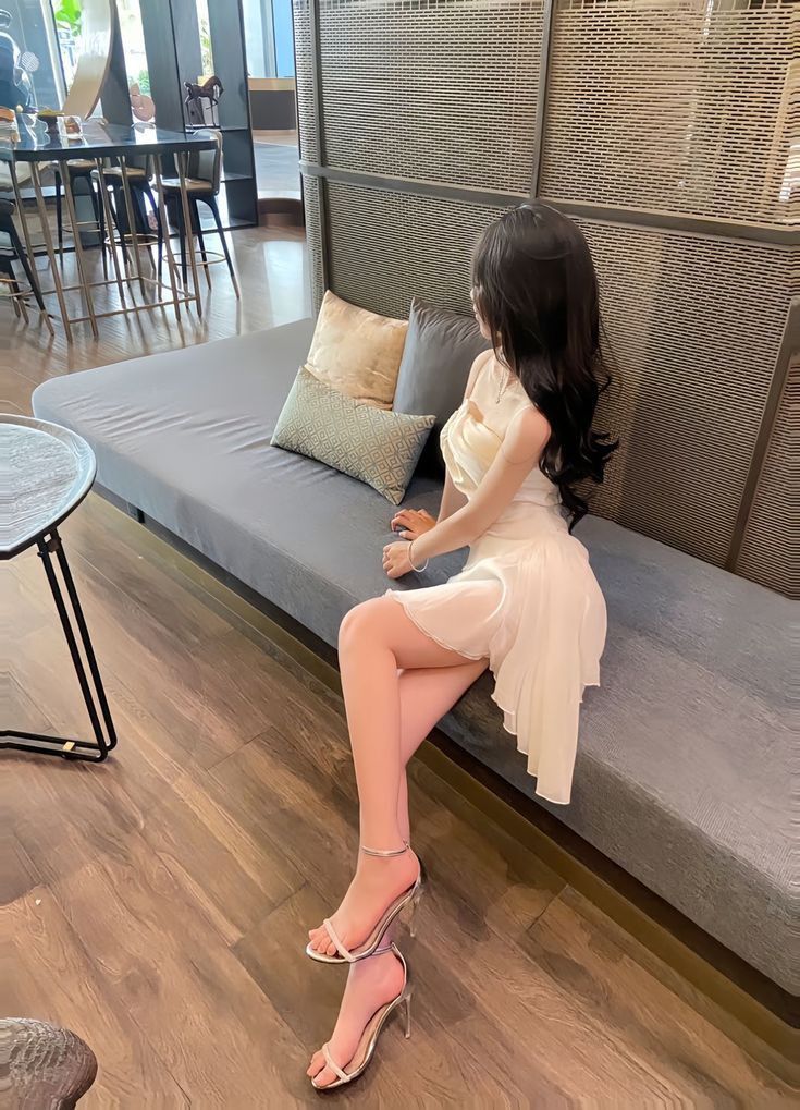 Gái xinh mặc đầm trắng ngồi trên ghế sofa