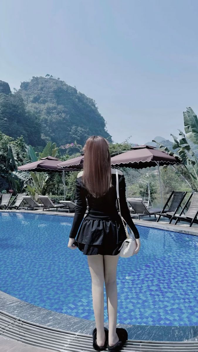 Gái xinh mặc váy đen bên bể bơi trong không gian tươi mát