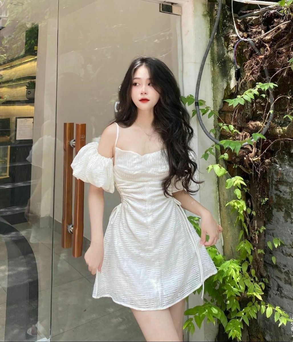 Gái xinh mặc váy trắng kiều dáng ngắn tự tin bên cây xanh