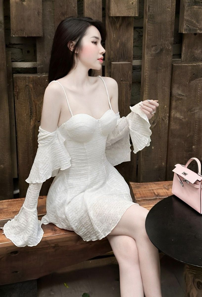 Gái xinh mặc váy trắng ngồi trên ghế gỗ tạo dáng thư giãn