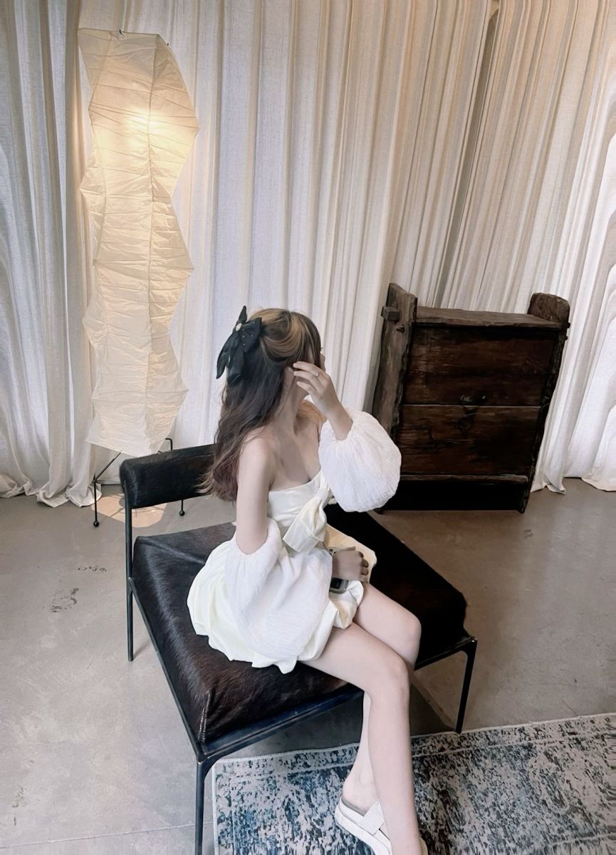 Gái xinh mặc váy trắng ngồi trên ghế sang trọng