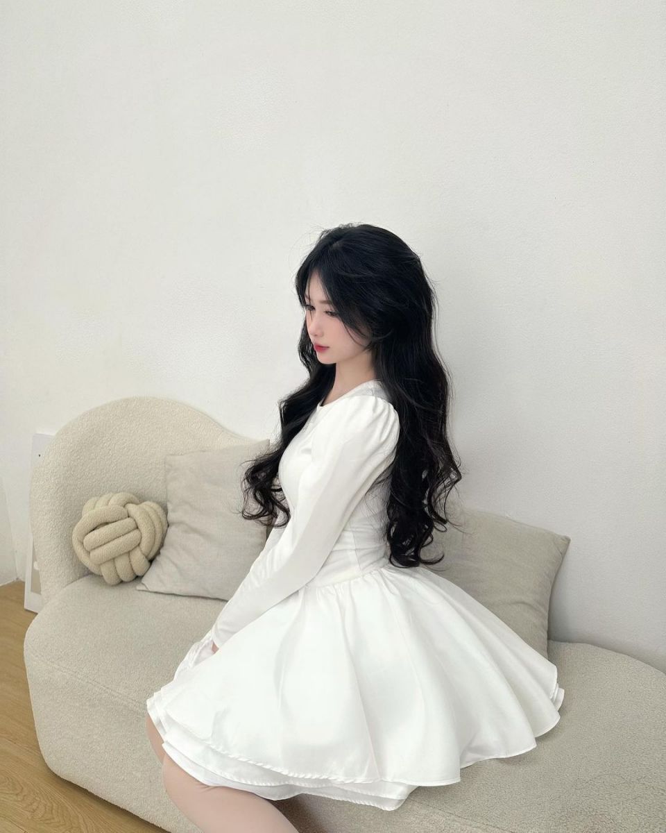 Gái xinh mặc váy trắng ngồi trên ghế sofa sang trọng