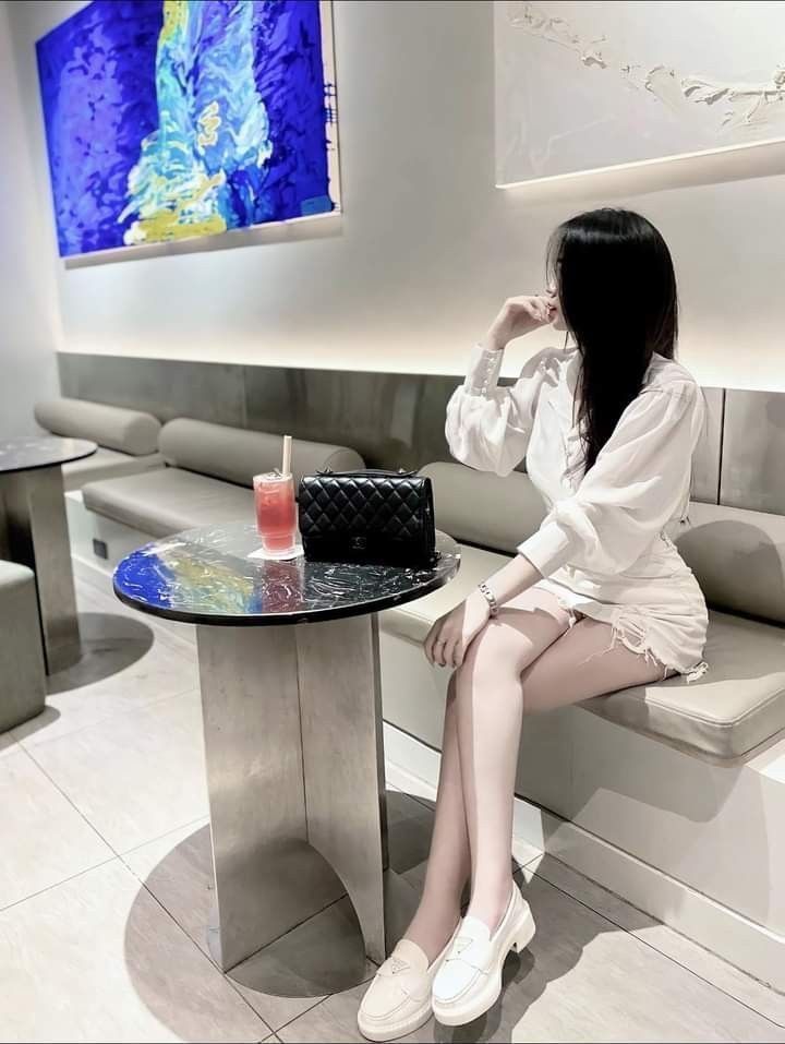 Gái xinh trong áo blouse trắng và chân váy ngắn tại quán cà phê