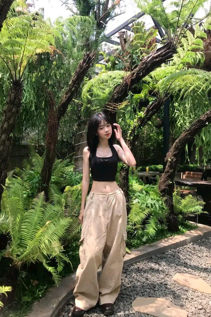 Gái xinh trong áo croptop đen và quần baggy giữa vườn xanh tươi