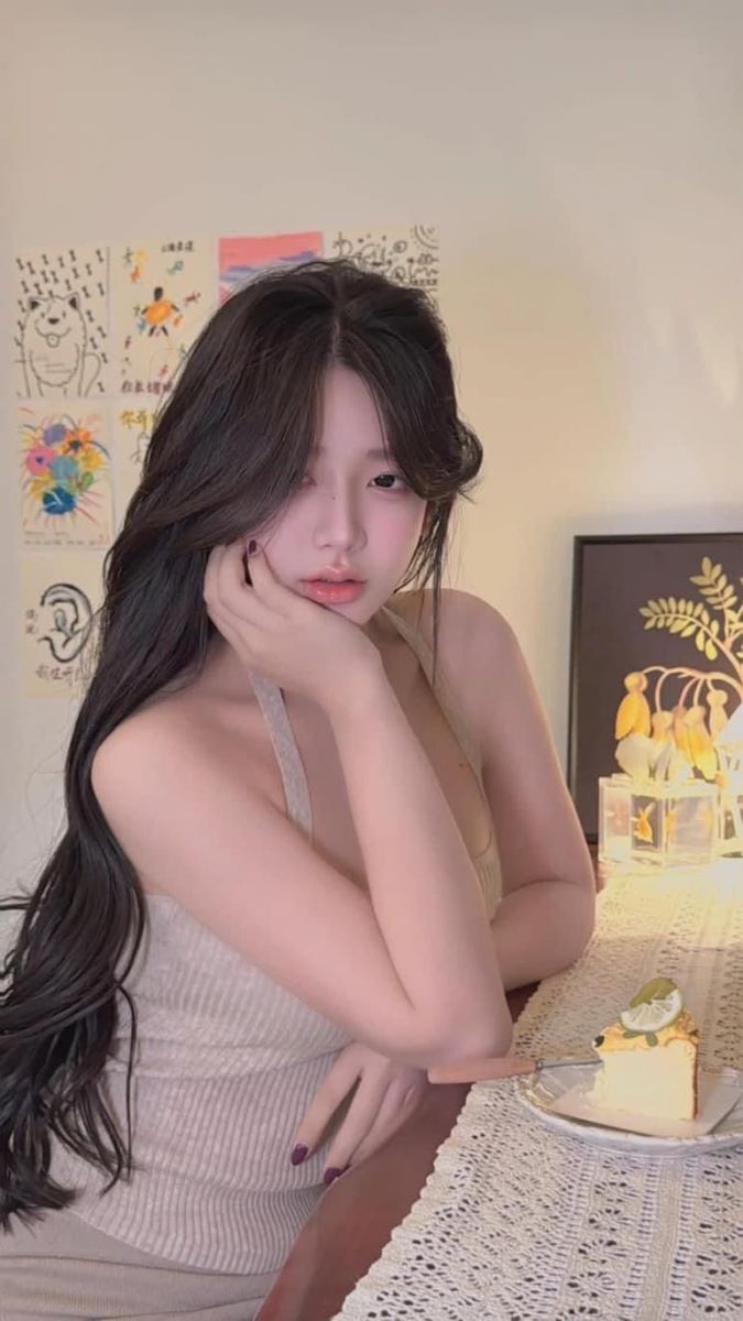 Gái xinh trong áo hai dây màu sáng bên bàn ăn