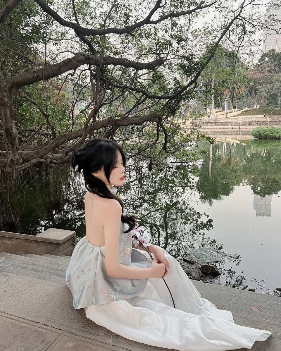 Gái xinh trong áo hai dây màu xanh và chân váy trắng bên bờ hồ