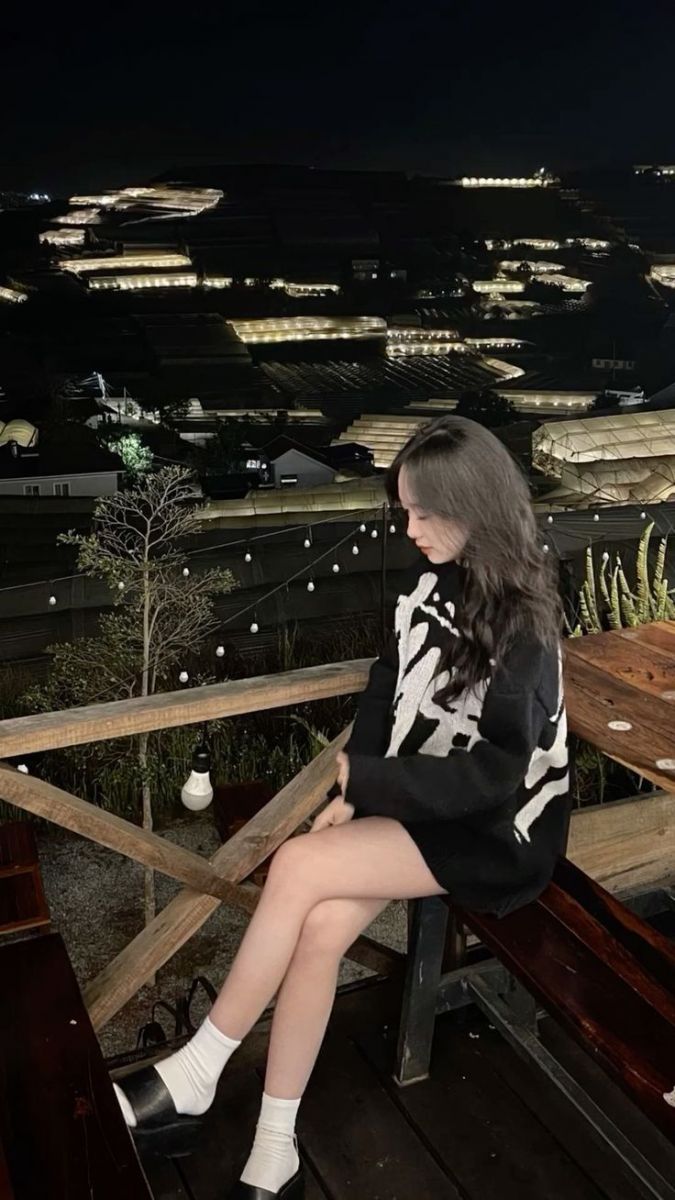 Gái xinh trong áo len trắng ngồi ngắm cảnh đêm