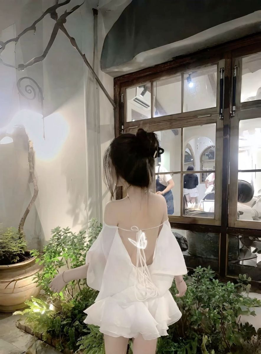 Gái xinh trong chiếc váy trắng nhìn ra cửa sổ quán cà phê