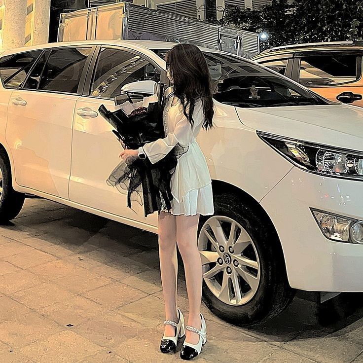 Gái xinh trong váy trắng cầm hoa bên xe ô tô màu trắng