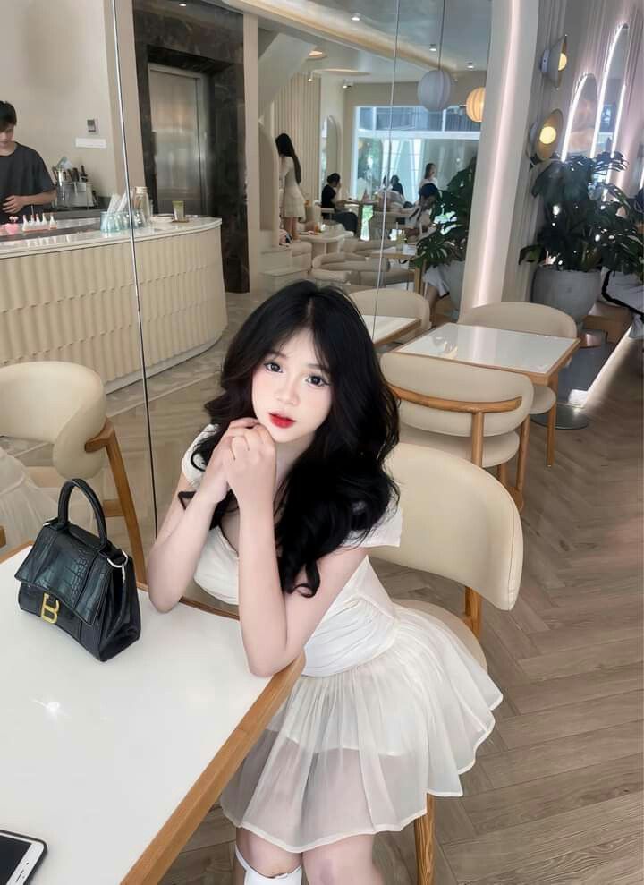 Gái xinh trong váy trắng ngồi bên bàn tay che mặt
