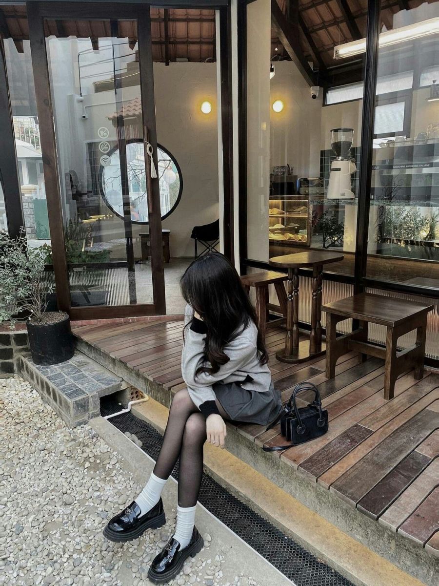 Gái xinh với áo len xám và chân váy tối tại quán cà phê