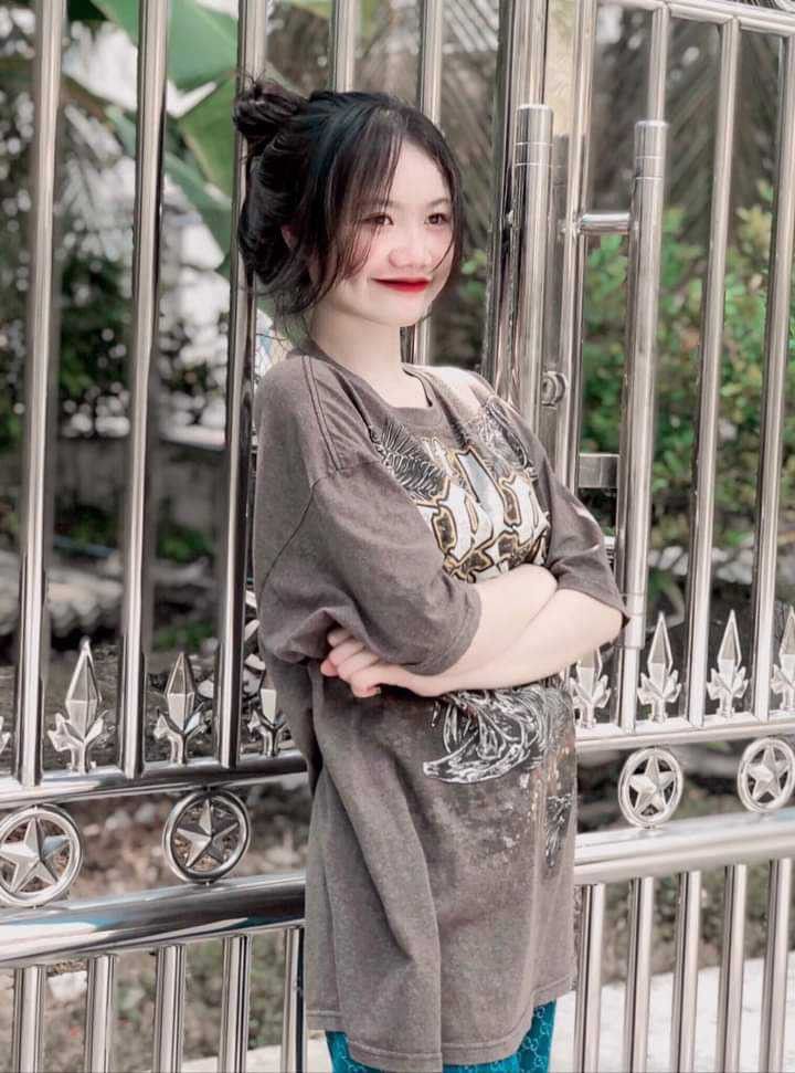 Gái Trẻ Mặc Áo Phông Rộng Tựa Vào Hàng Rào Kim Loại