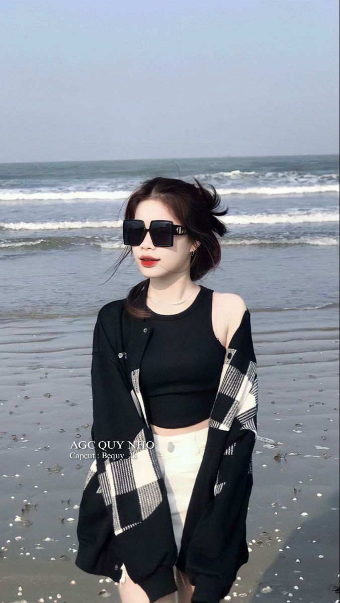 Ảnh cô gái đẹp mặc áo crop top đen và áo khoác caro bên bờ biển