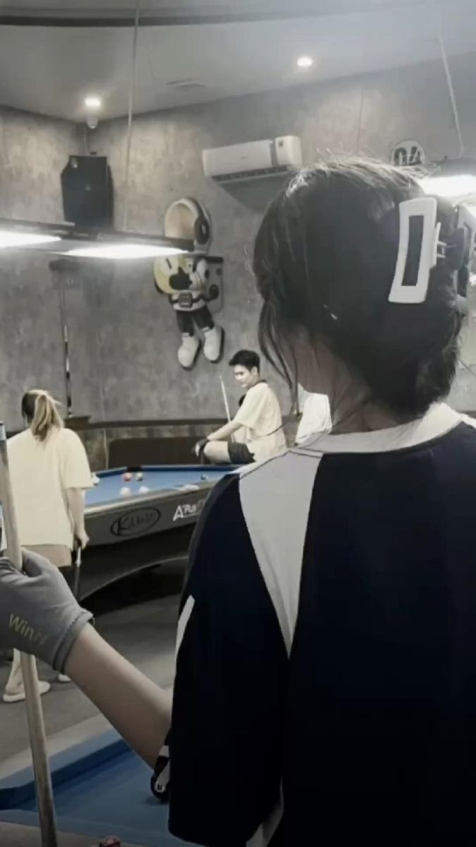 Ảnh cô gái trong quán bi-a mặc áo thun màu tối sọc trắng cam