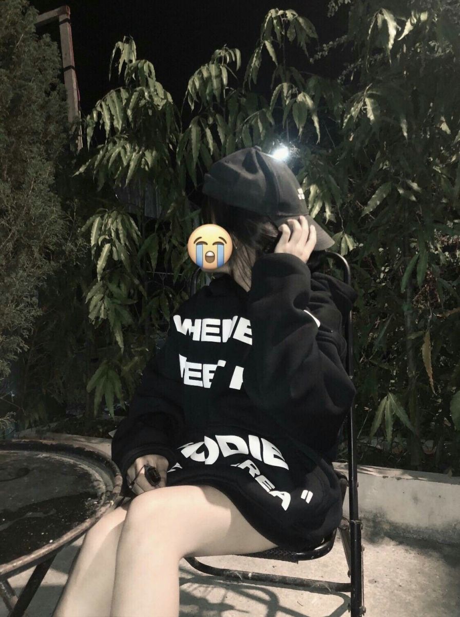 Ảnh gái mặc áo hoodie đen ngồi trên ghế tay đưa lên che mặt