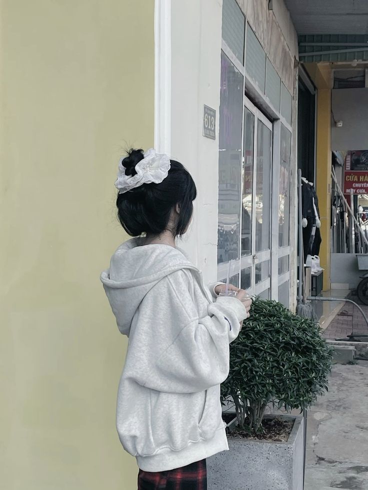 Ảnh gái mặc áo hoodie màu xám bên cây bụi nhỏ