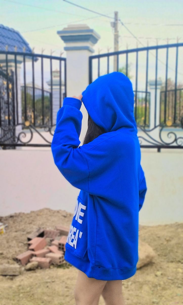 Ảnh gái mặc áo hoodie màu xanh dương bên hàng rào