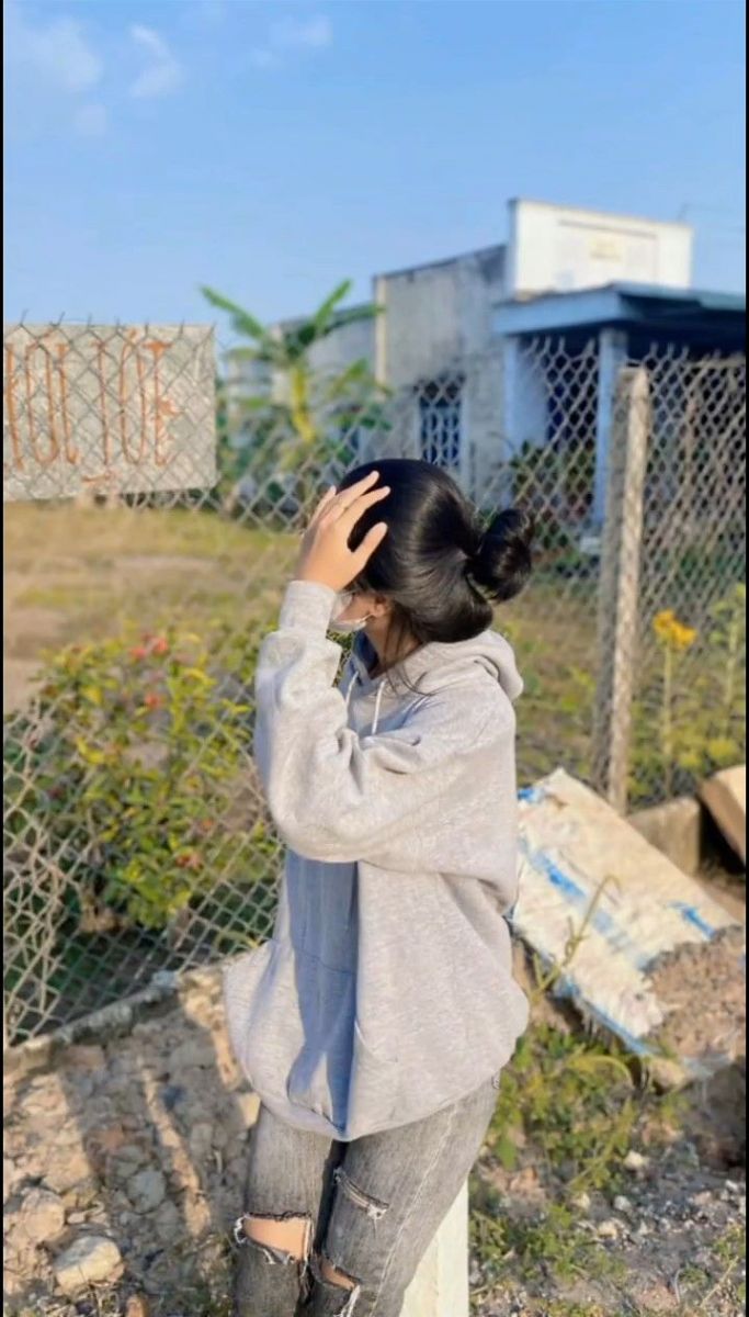 Ảnh gái mặc áo hoodie xám bên khu đất trống