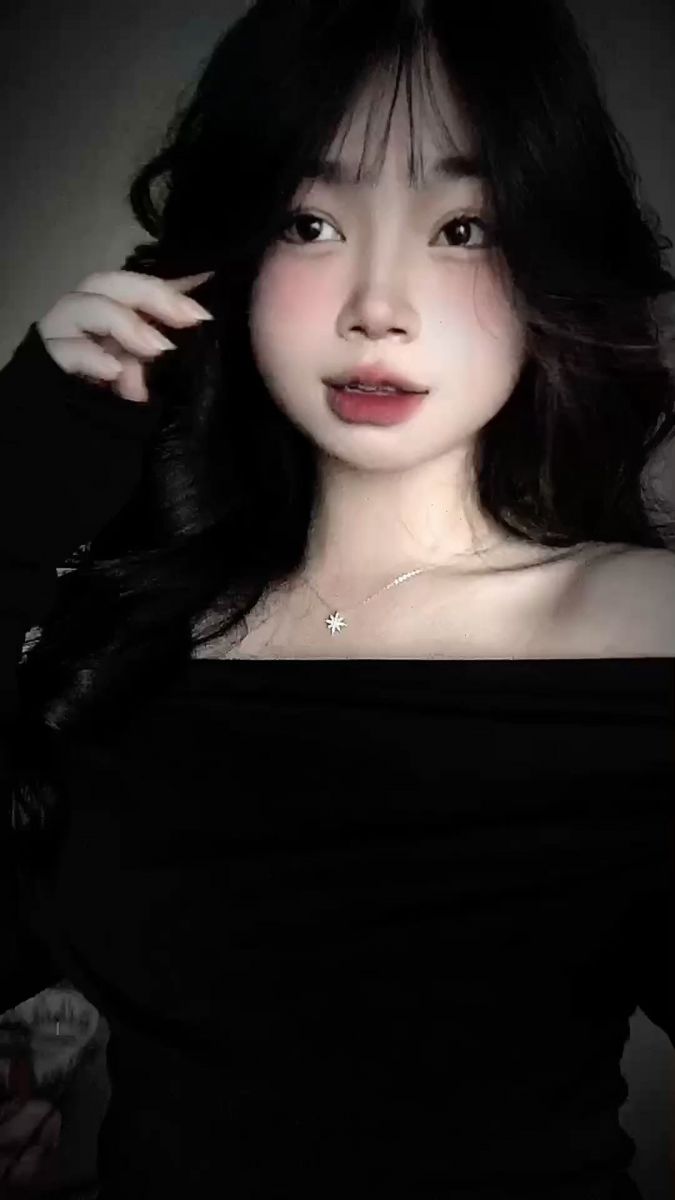 Ảnh gái mặc áo sơ mi đen tạo dáng nhẹ nhàng trong không gian tối