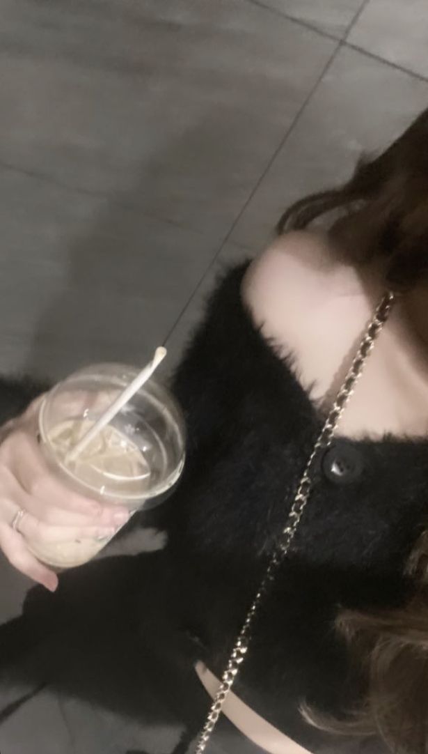 Ảnh gái trẻ mặc áo crop top đen cầm ly trà sữa tại địa điểm xinh xắn