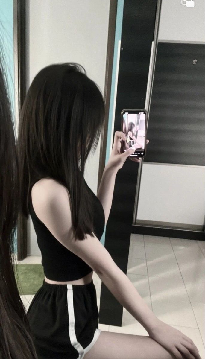 Ảnh gái trẻ mặc áo crop top đen và quần short đen chụp selfie