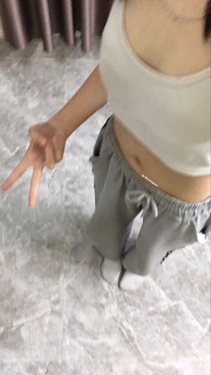 Ảnh gái trẻ mặc áo crop top trắng và quần thể thao xám