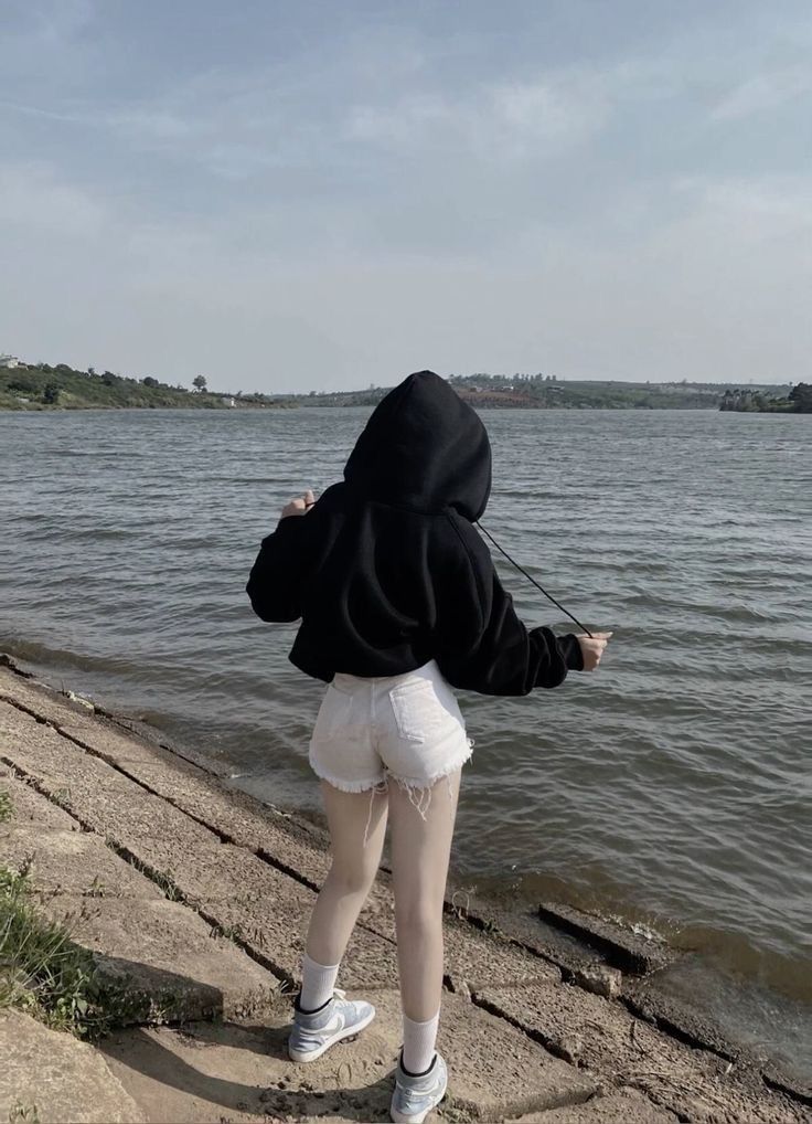 Ảnh gái trẻ mặc áo hoodie đen và quần shorts bên bờ sông Tây Nam