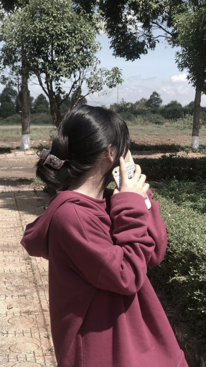 Ảnh gái trẻ mặc áo hoodie đỏ giữa khu vườn xanh