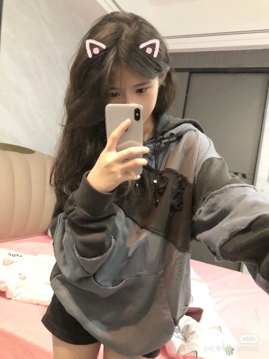 Ảnh gái trẻ mặc áo hoodie màu xám đen chụp selfie trong phòng ngủ