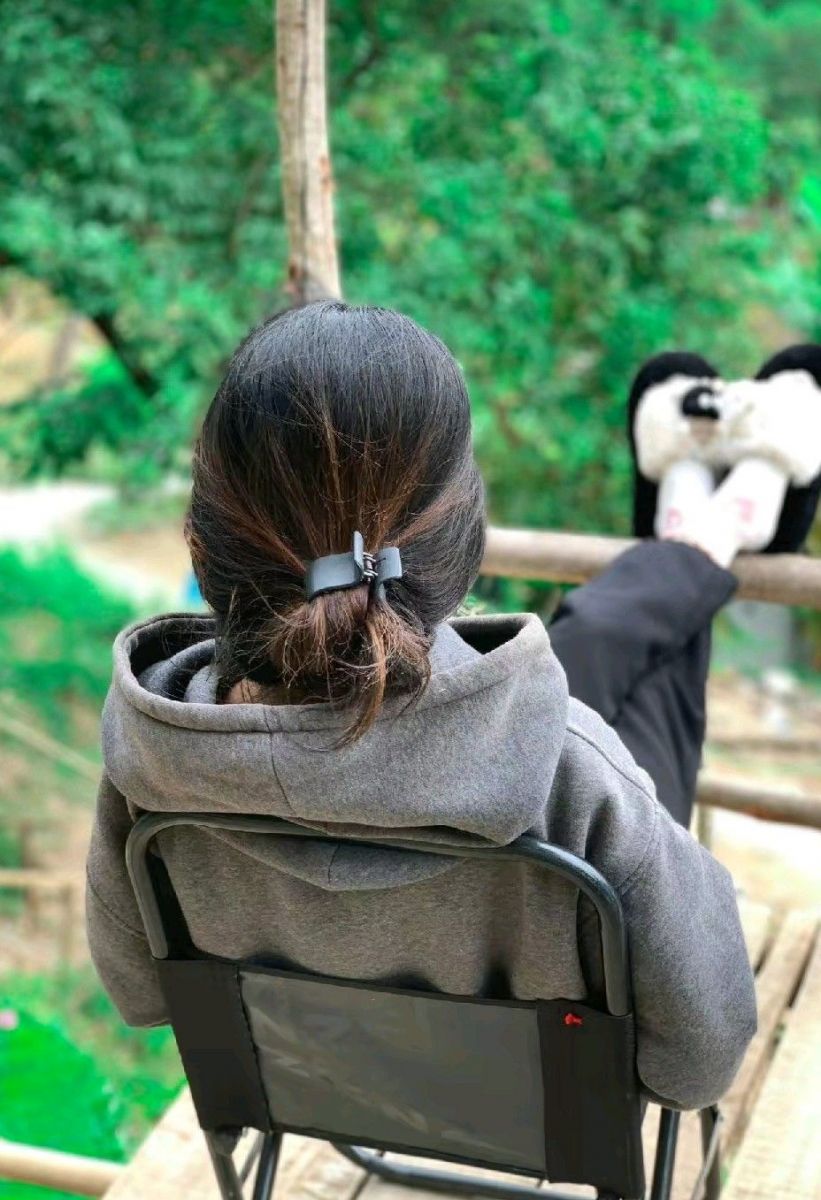 Ảnh gái trẻ mặc áo hoodie ngồi thư giãn giữa rừng cây