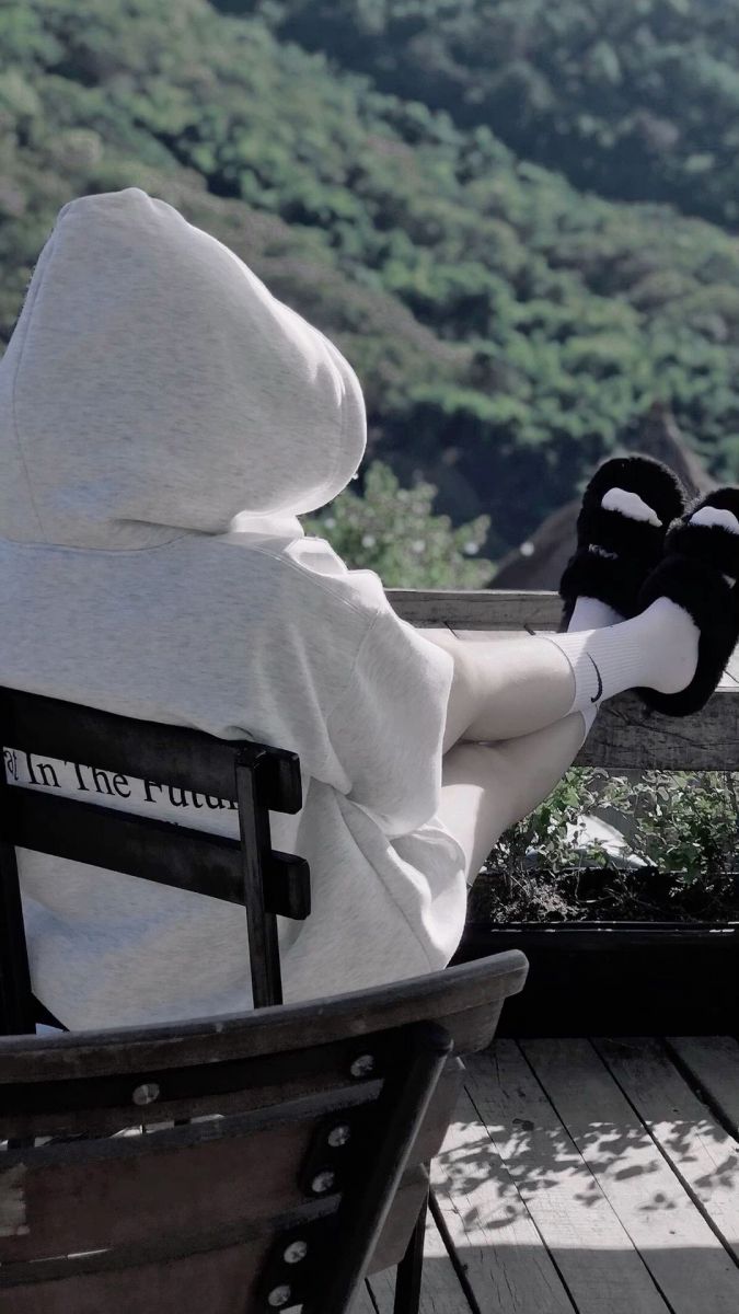 Ảnh gái trẻ mặc áo hoodie trắng ngồi thư giãn trên ghế gỗ