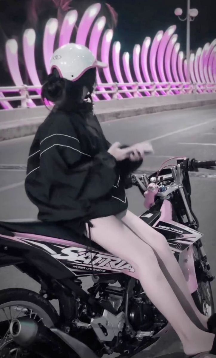 Ảnh gái trẻ mặc áo khoác đen ngồi trên xe máy màu hồng