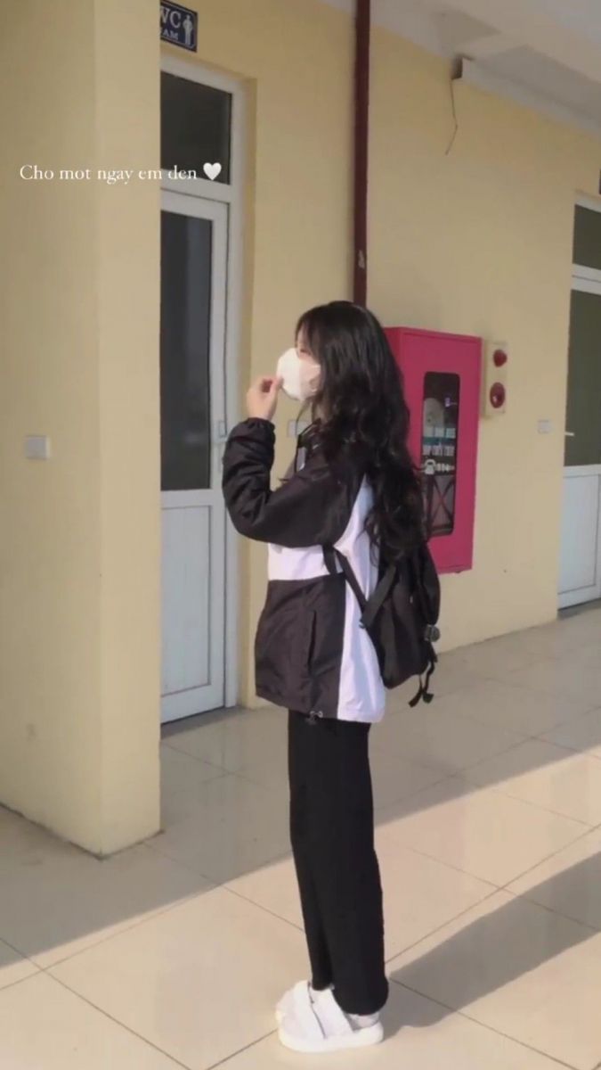Ảnh gái trẻ mặc áo khoác đen, quần đen và giày thể thao trắng