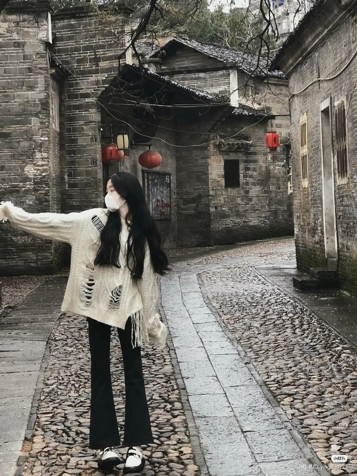 Ảnh gái trẻ mặc áo len trắng và quần đen giữa đường phố