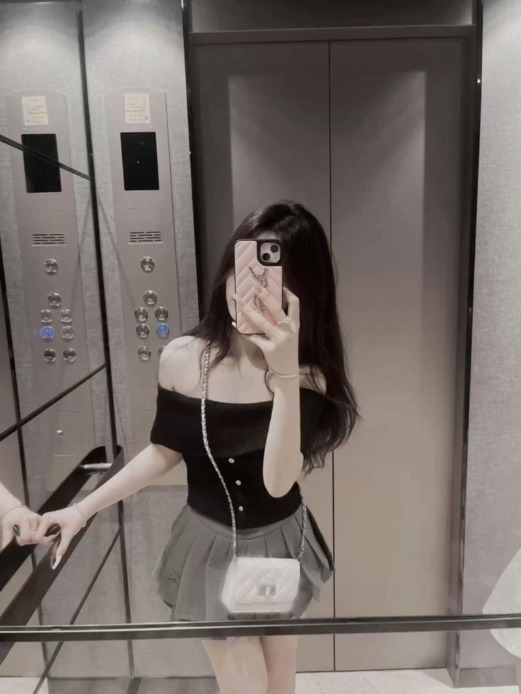 Ảnh gái trẻ mặc áo phông cổ trễ và chân váy ngắn chụp selfie trong thang máy