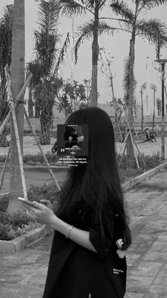 Ảnh gái trẻ mặc áo phông đen chụp với điện thoại tại công viên xanh