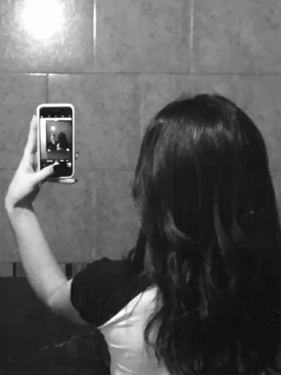 Ảnh gái trẻ mặc áo phông đen và trắng chụp selfie trong phòng tắm