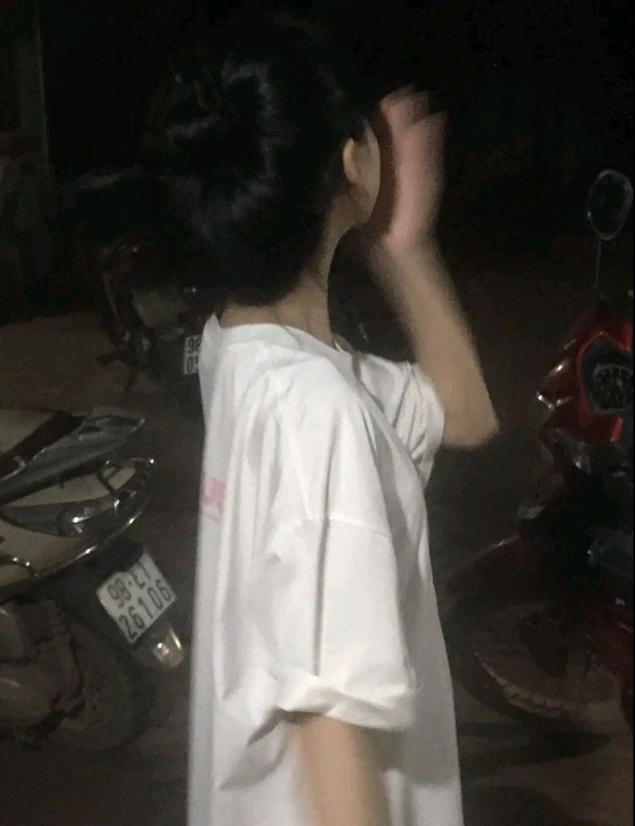 Ảnh gái trẻ mặc áo phông rộng dịu dàng ở bãi xe buổi tối