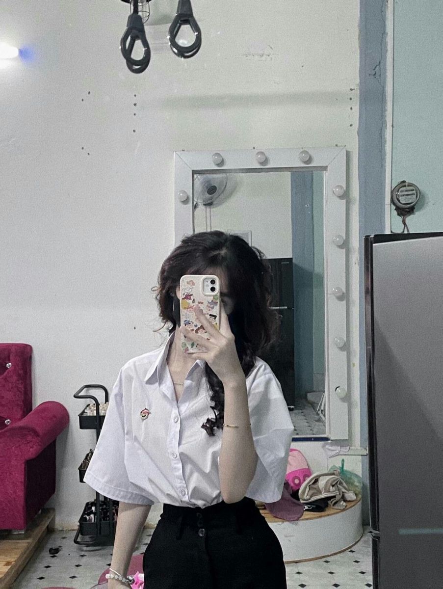 Ảnh gái trẻ mặc áo sơ mi trắng và quần đen chụp selfie trong phòng ngủ