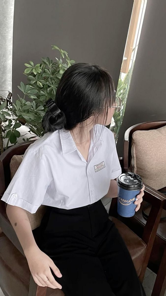 Ảnh gái trẻ mặc áo sơ mi trắng và quần đen trong quán cà phê
