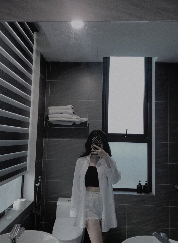 Ảnh gái trẻ mặc áo sơ mi trắng và quần short đen trong phòng tắm