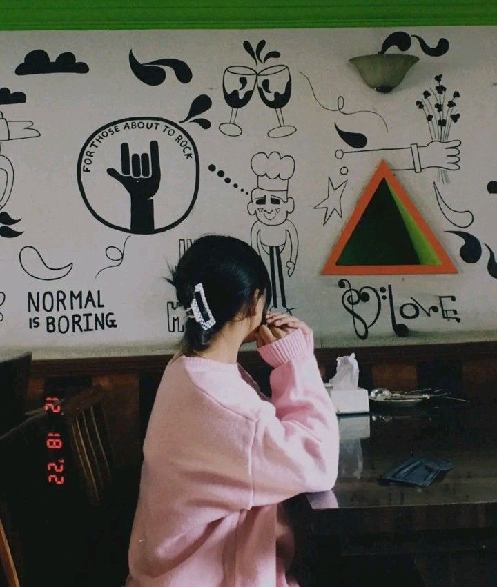 Ảnh gái trẻ mặc áo sweater hồng ngồi trong quán cà phê