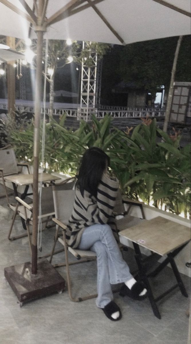 Ảnh gái trẻ mặc áo sweater sọc và quần jeans ngồi ở quán cà phê
