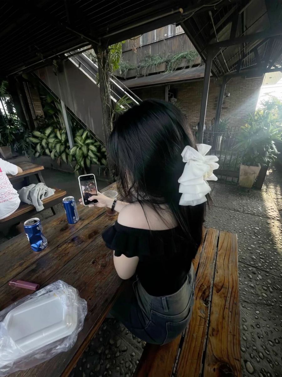 Ảnh gái trẻ mặc áo thun đen và quần jean tại quán cà phê