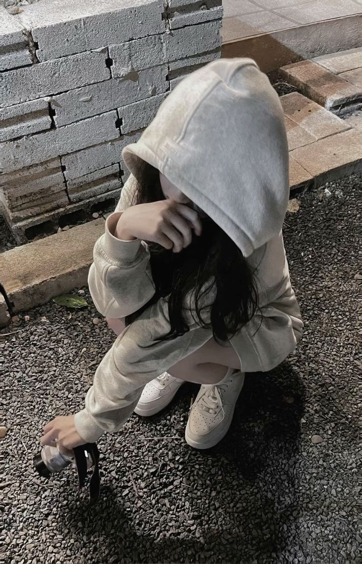 Ảnh gái trẻ mặc hoodie sáng màu ngồi xóm trên mặt đất