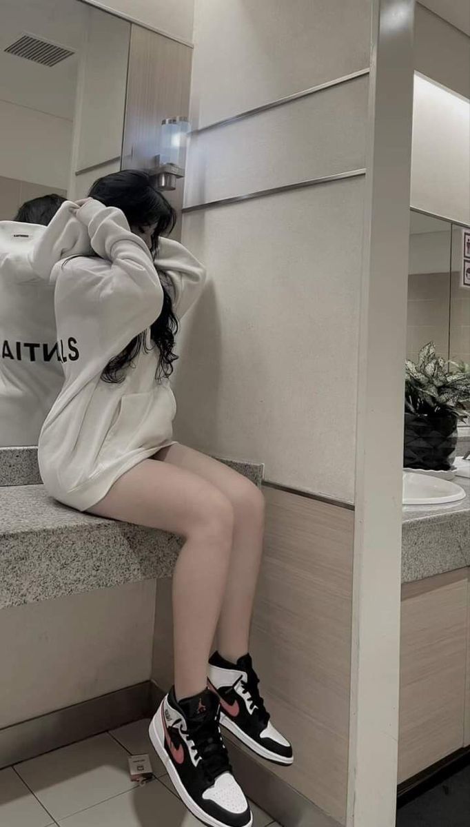 Ảnh gái trẻ mặc hoodie trắng ngồi trên bể đá